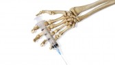 Still Life of a Skeleton Hand Holding a Medical Hypodermic Needle on a White Background