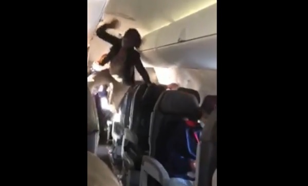 Image: Demon-possessed woman goes insane on airplane, screaming obscenities while climbing over seats